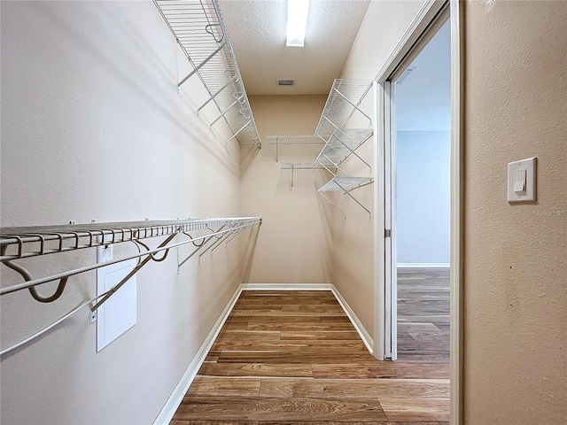 walk in closet with hardwood / wood-style flooring