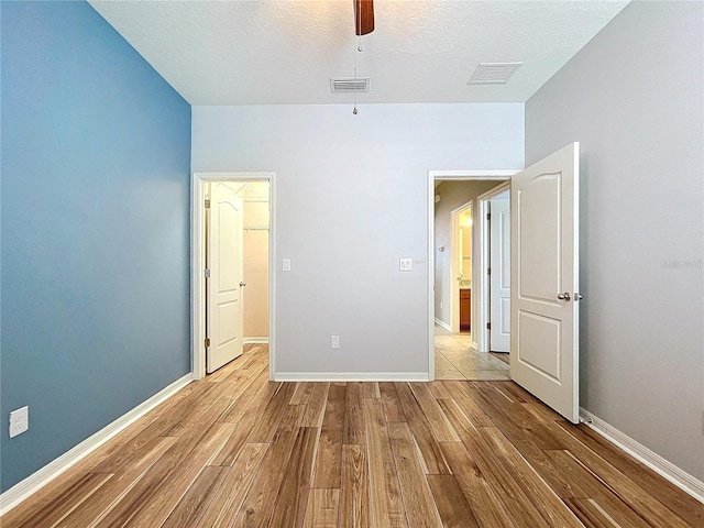 unfurnished bedroom with ceiling fan, a textured ceiling, and light hardwood / wood-style floors