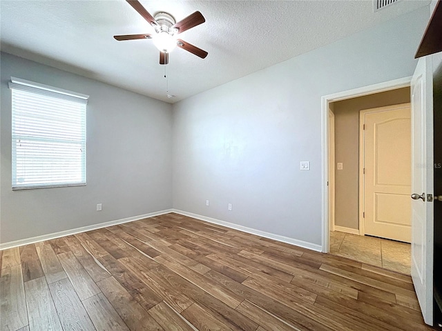 spare room featuring ceiling fan, wood-type flooring, and a textured ceiling