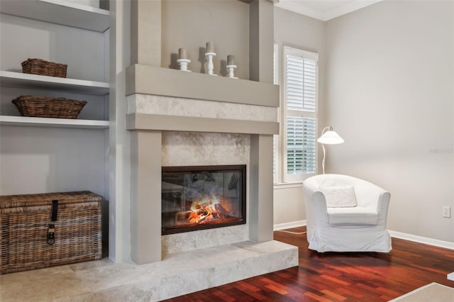 sitting room with a premium fireplace, wood-type flooring, a wealth of natural light, and crown molding