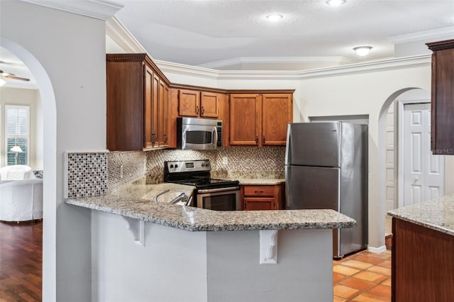 kitchen with stainless steel appliances, a kitchen bar, light stone countertops, and decorative backsplash