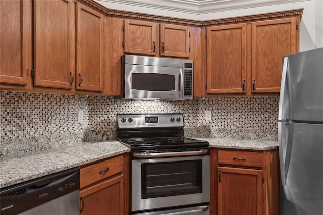 kitchen with light stone counters, ornamental molding, stainless steel appliances, and decorative backsplash