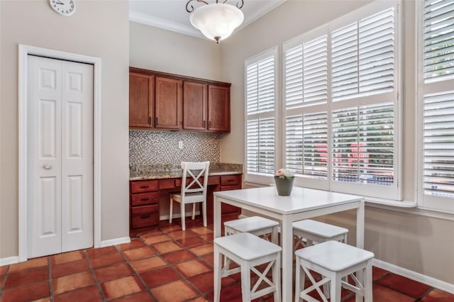 kitchen with ornamental molding, built in desk, and decorative backsplash