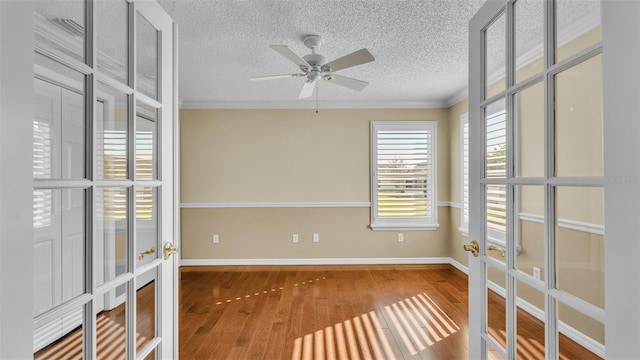 empty room with ceiling fan, french doors, wood-type flooring, and ornamental molding