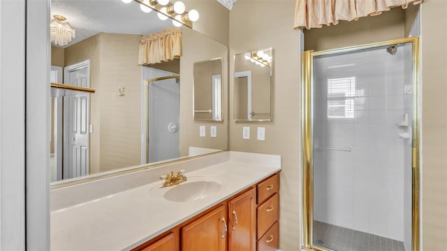 bathroom with a shower with door, vanity, and a textured ceiling