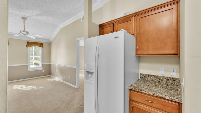 kitchen with ceiling fan, white fridge with ice dispenser, light stone counters, a textured ceiling, and ornamental molding