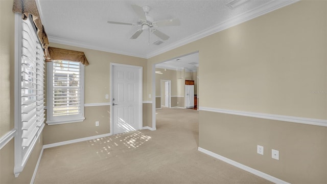 empty room featuring ceiling fan, light colored carpet, a textured ceiling, and ornamental molding