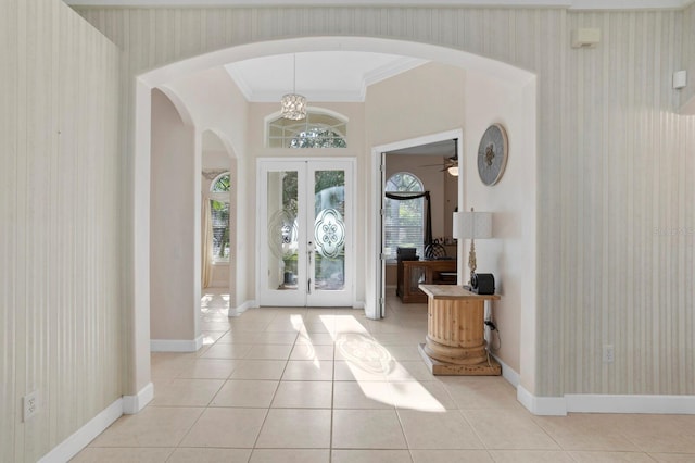 tiled entrance foyer with ornamental molding and french doors