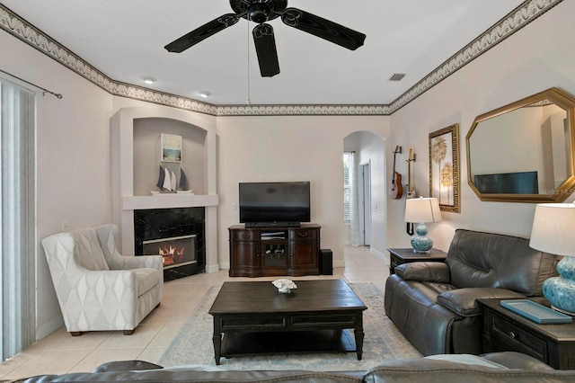 living room featuring ceiling fan, a fireplace, and light tile patterned floors