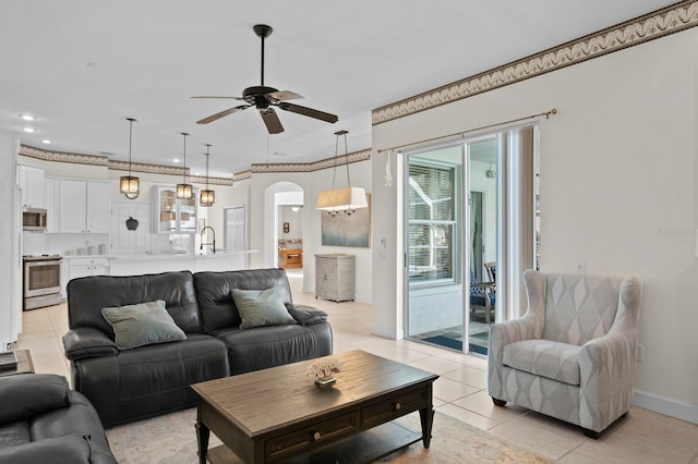 tiled living room with crown molding, sink, and ceiling fan