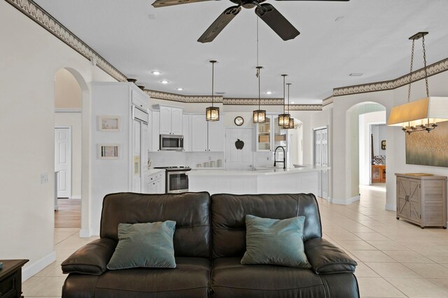 living room featuring light tile patterned floors, crown molding, sink, and ceiling fan