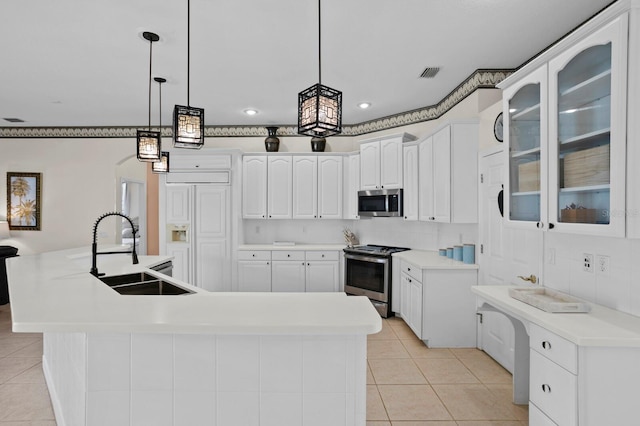 kitchen with sink, appliances with stainless steel finishes, white cabinetry, an island with sink, and decorative light fixtures