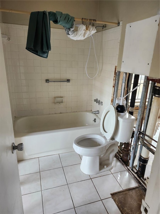 bathroom with tile patterned floors, tiled shower / bath combo, and toilet