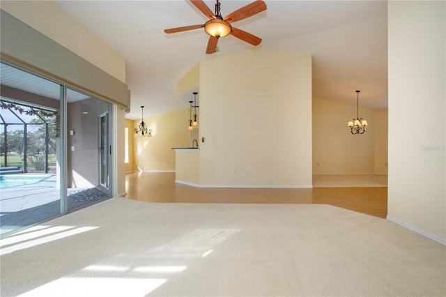 carpeted spare room with vaulted ceiling and ceiling fan with notable chandelier