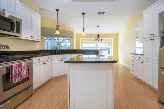 kitchen with stainless steel appliances, vaulted ceiling, a center island, and white cabinets