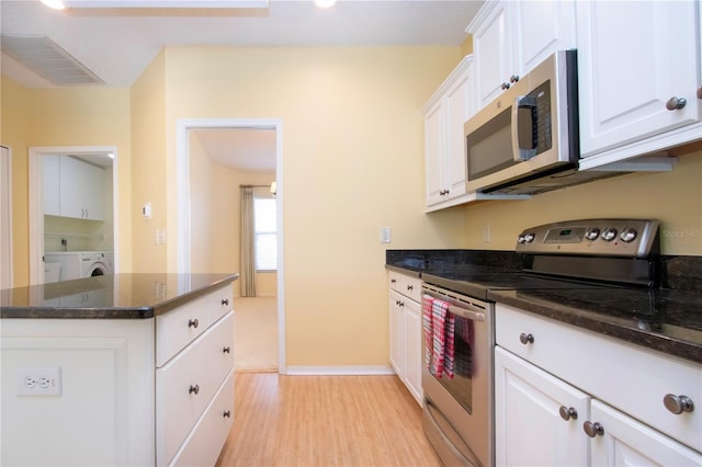 kitchen featuring white cabinetry, stainless steel appliances, washer / clothes dryer, and dark stone countertops