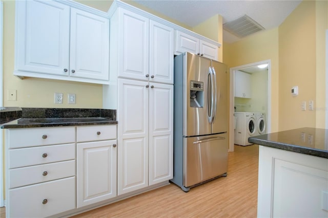 kitchen featuring white cabinetry, dark stone counters, independent washer and dryer, stainless steel refrigerator with ice dispenser, and light wood-type flooring