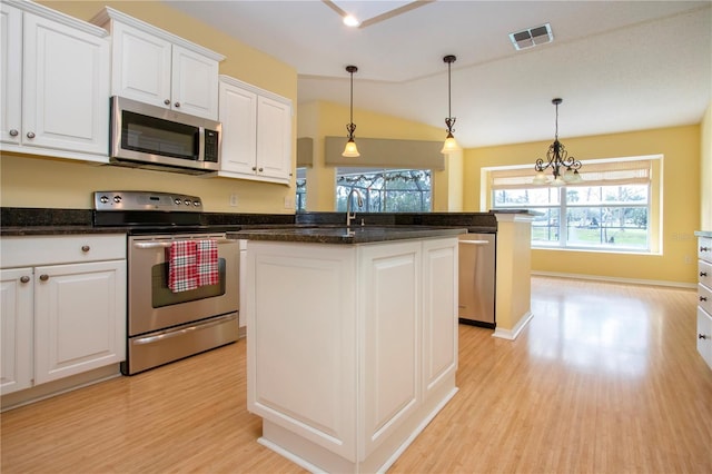 kitchen with appliances with stainless steel finishes, a kitchen island, white cabinetry, sink, and hanging light fixtures