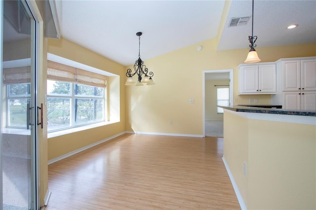 kitchen featuring lofted ceiling, decorative light fixtures, light hardwood / wood-style flooring, and white cabinets