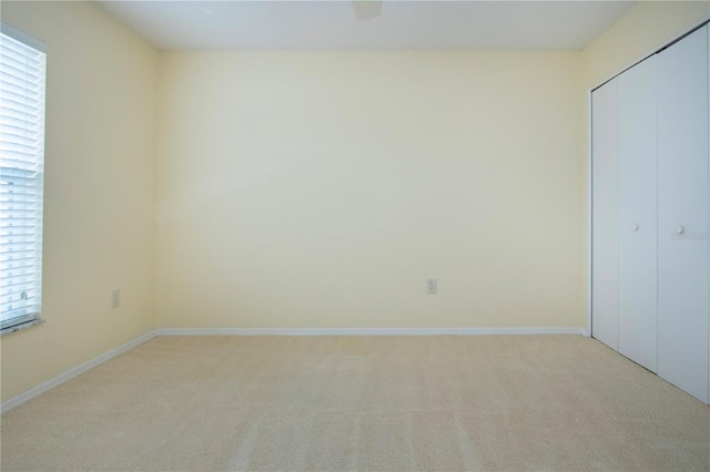 unfurnished bedroom with light colored carpet, a closet, and ceiling fan