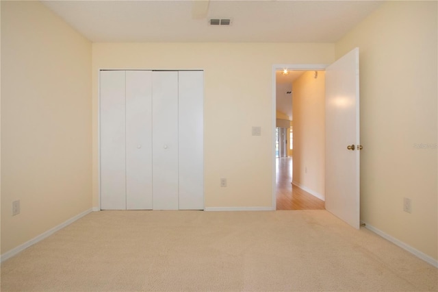 unfurnished bedroom with light carpet and a closet