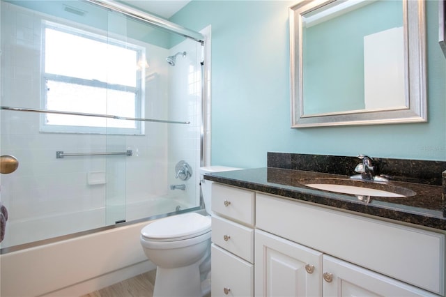 full bathroom with toilet, vanity, and bath / shower combo with glass door