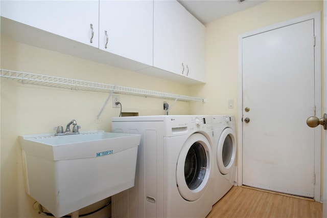 washroom featuring cabinets, sink, washer and dryer, and light wood-type flooring