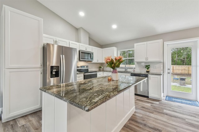 kitchen featuring a center island, white cabinets, stainless steel appliances, and vaulted ceiling