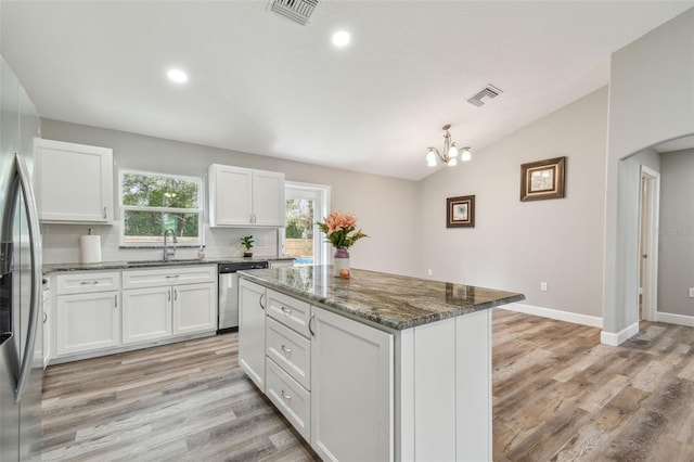 kitchen featuring stainless steel appliances, backsplash, dark stone counters, lofted ceiling, and white cabinets