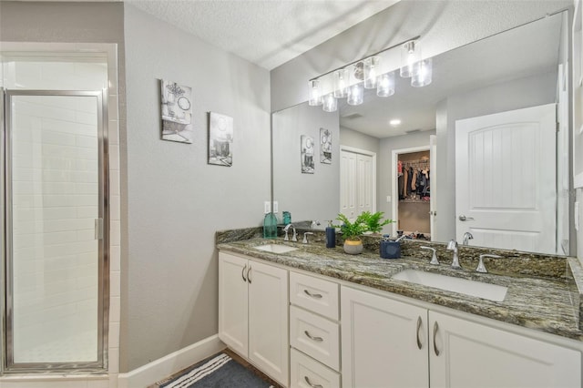 bathroom with vanity, a textured ceiling, and an enclosed shower