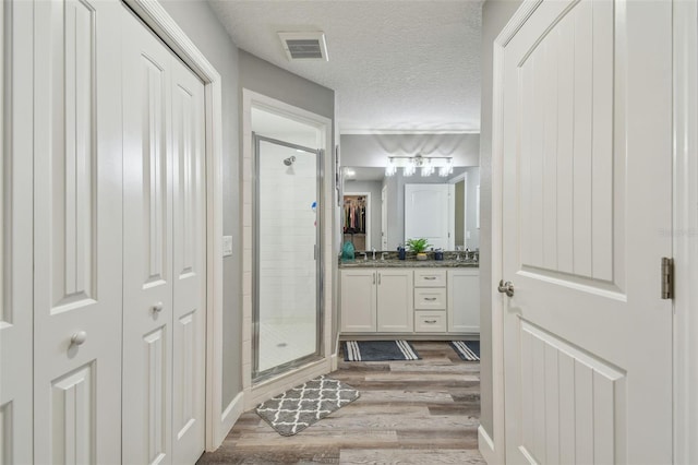 bathroom featuring a textured ceiling, vanity, walk in shower, and hardwood / wood-style floors