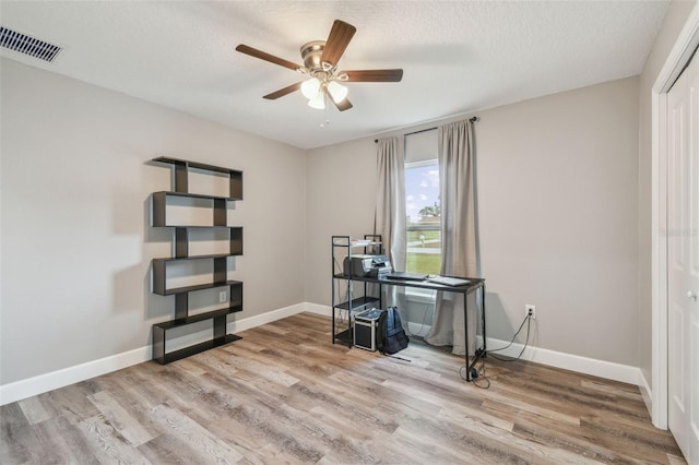 unfurnished office with ceiling fan, a textured ceiling, and hardwood / wood-style flooring