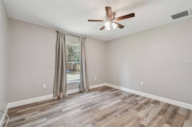 empty room with a textured ceiling, light wood-type flooring, and ceiling fan