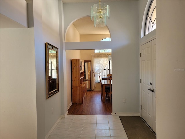 tiled foyer entrance with a high ceiling and an inviting chandelier