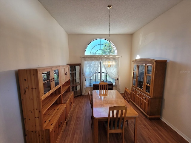 dining area featuring a textured ceiling, a notable chandelier, and dark wood-type flooring