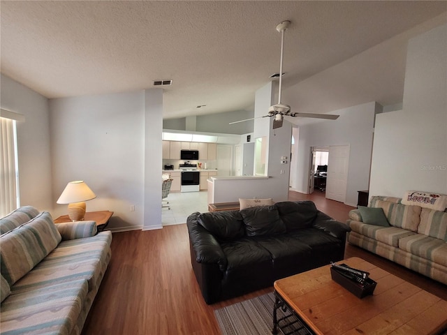 living room with hardwood / wood-style floors, ceiling fan, lofted ceiling, and a textured ceiling