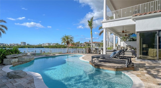 view of swimming pool featuring ceiling fan, a patio area, and a water view