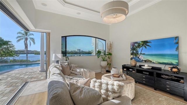 living room featuring a tray ceiling, crown molding, a water view, and light hardwood / wood-style floors