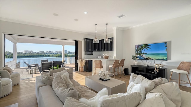 living room with a water view, ornamental molding, and light hardwood / wood-style flooring