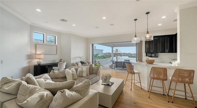 living room with a water view, light hardwood / wood-style floors, and ornamental molding