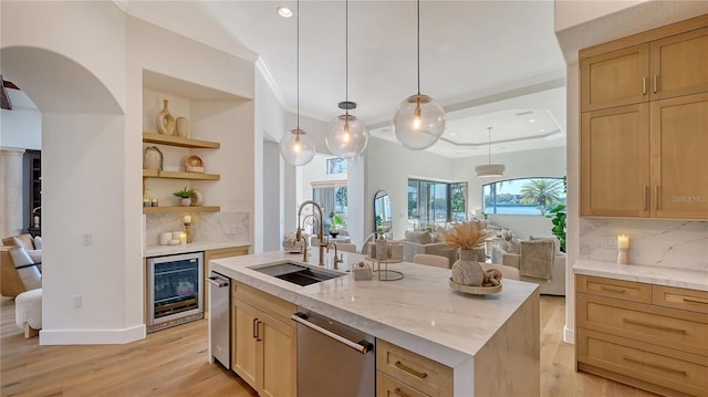 kitchen featuring backsplash, sink, wine cooler, hanging light fixtures, and an island with sink