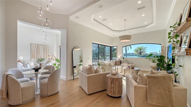 living room with a raised ceiling, a towering ceiling, crown molding, and light hardwood / wood-style flooring