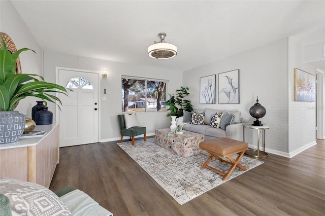 living room with dark wood-type flooring and brick wall