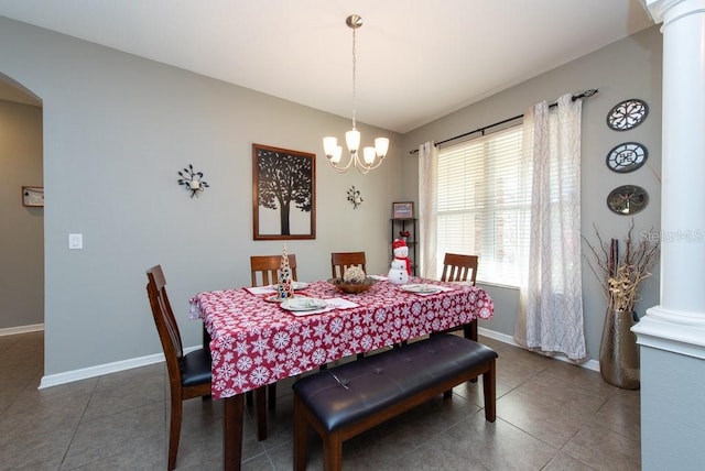 dining area featuring decorative columns, a chandelier, and dark tile patterned flooring