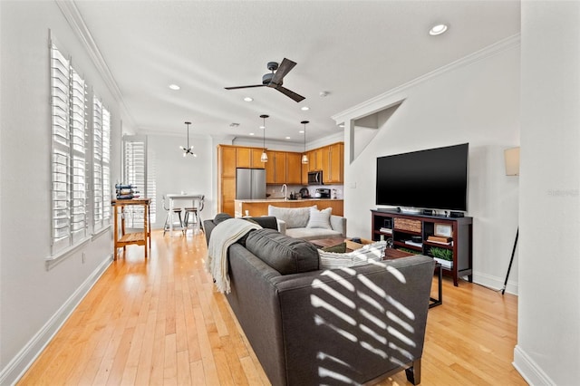 living room featuring light hardwood / wood-style floors, ceiling fan, ornamental molding, and sink