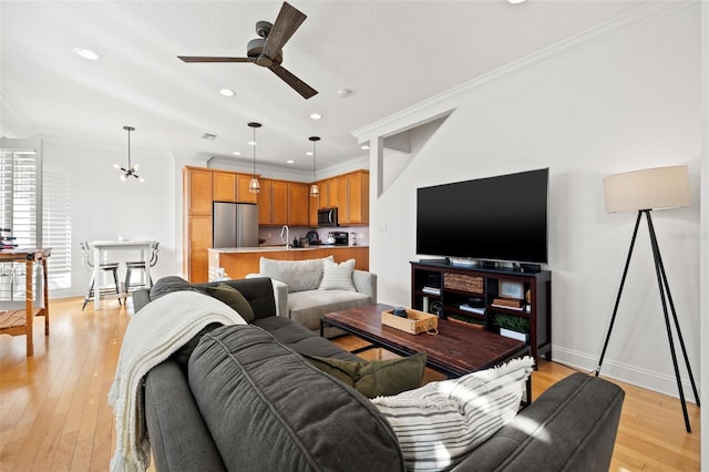 living room featuring ceiling fan with notable chandelier, light hardwood / wood-style floors, and ornamental molding