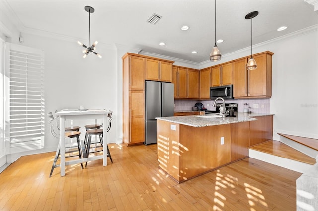 kitchen featuring kitchen peninsula, crown molding, decorative light fixtures, and appliances with stainless steel finishes