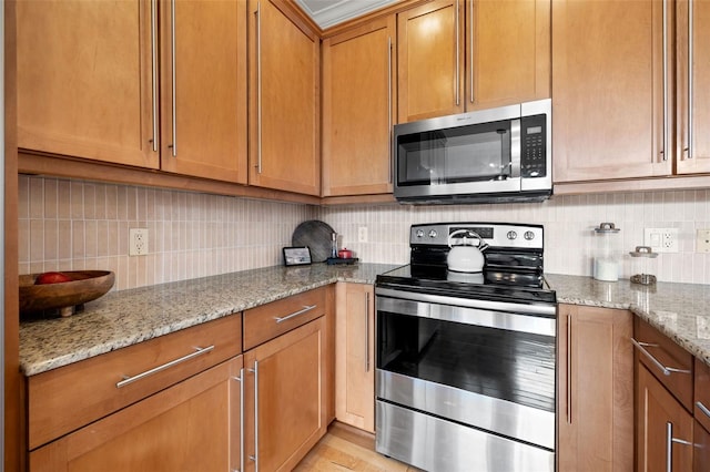 kitchen with light stone countertops, stainless steel appliances, and tasteful backsplash