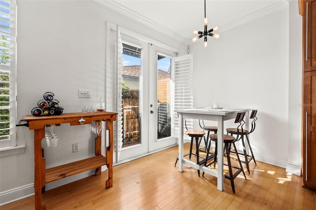 dining room with light wood-type flooring, crown molding, and an inviting chandelier