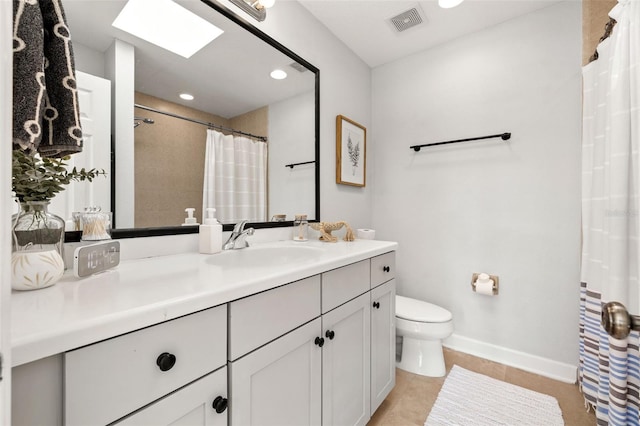 bathroom with a skylight, tile patterned flooring, vanity, and toilet